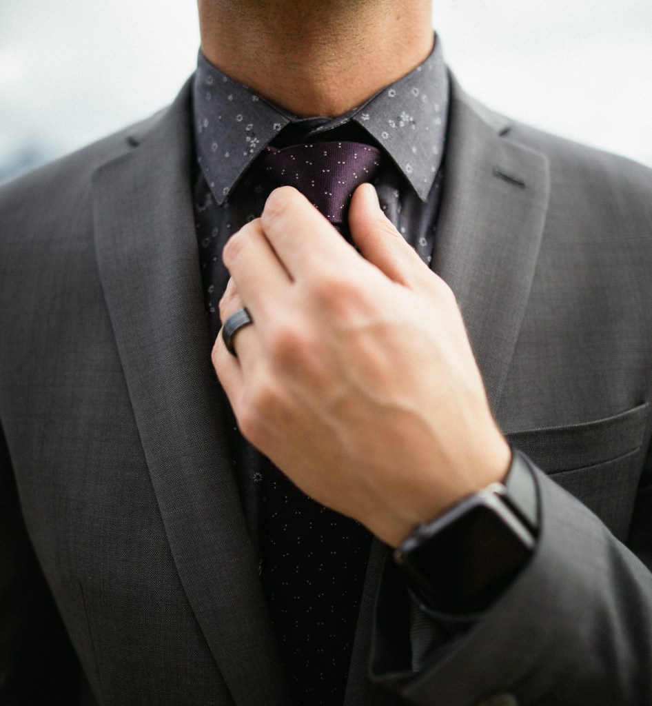 A man adjusting his tie, referring to a controversy involving Apple Watches