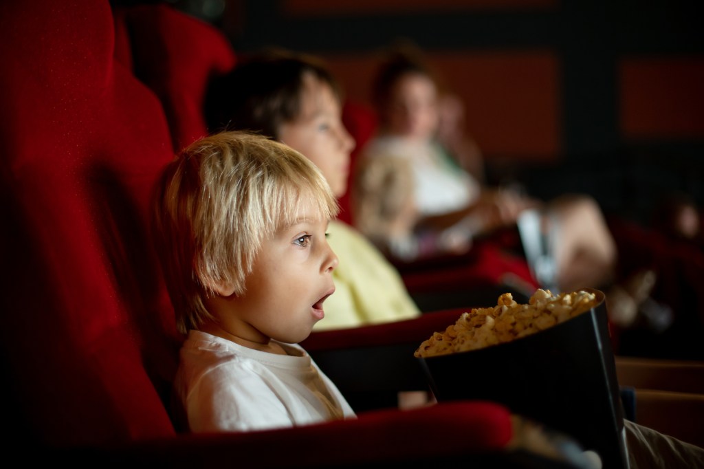 Guy in the cinema enjoying a movie while eating popcorn, with a glimpse of La Parka in the movie.