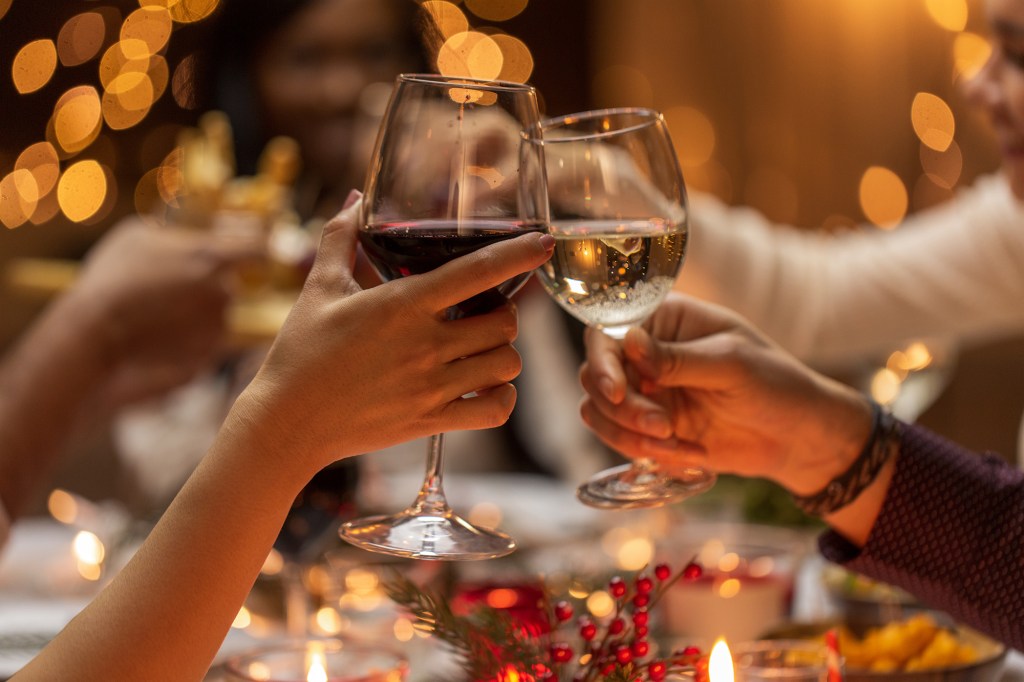 Close-up of a group of people holding glasses of wine at a Christmas dinner