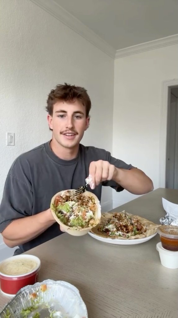 A hand holding a customizable Chipotle bowl filled with fresh ingredients