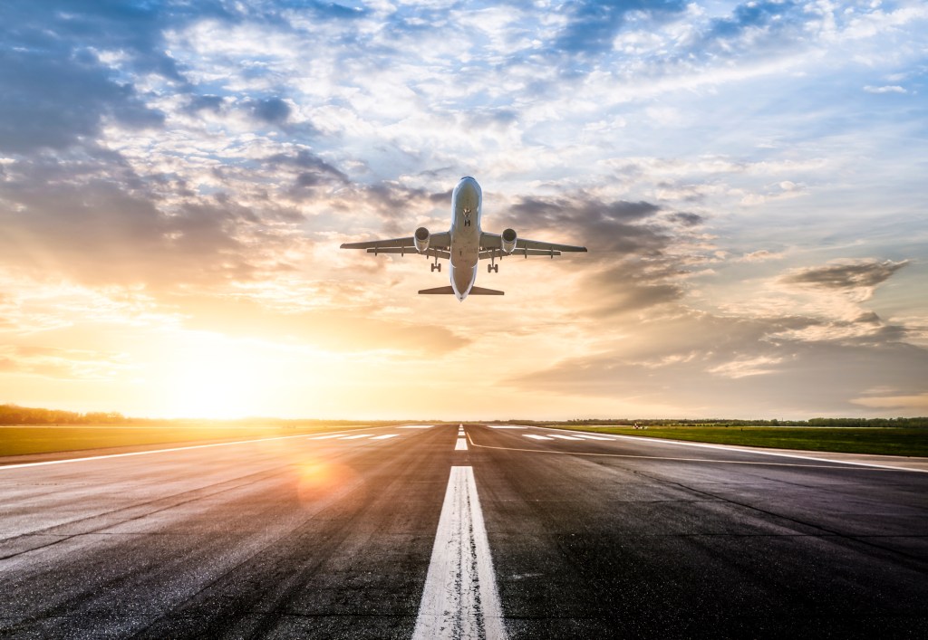 Passenger plane rising to sun rising on a runway