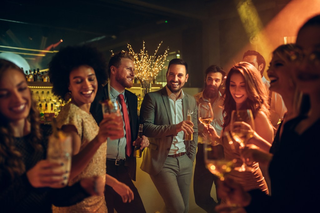 A cheerful group of friends celebrating, dancing and drinking in a nightclub