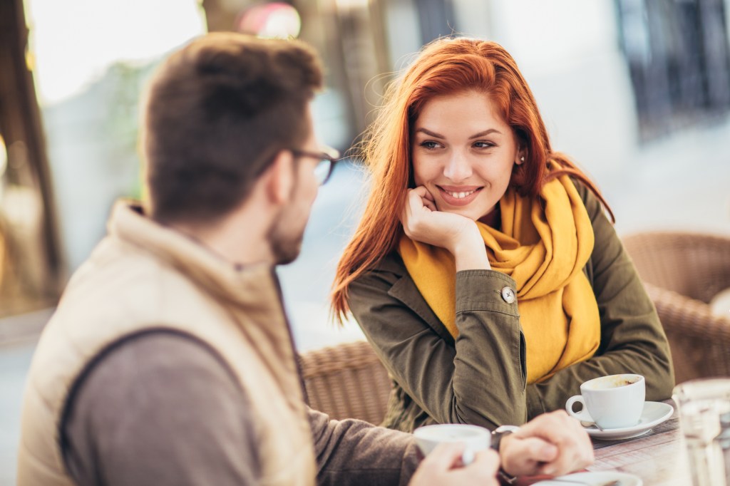 Rachelle Lefevre and an unidentified man sitting on a cafeteria table in nature, drinking coffee and being in love