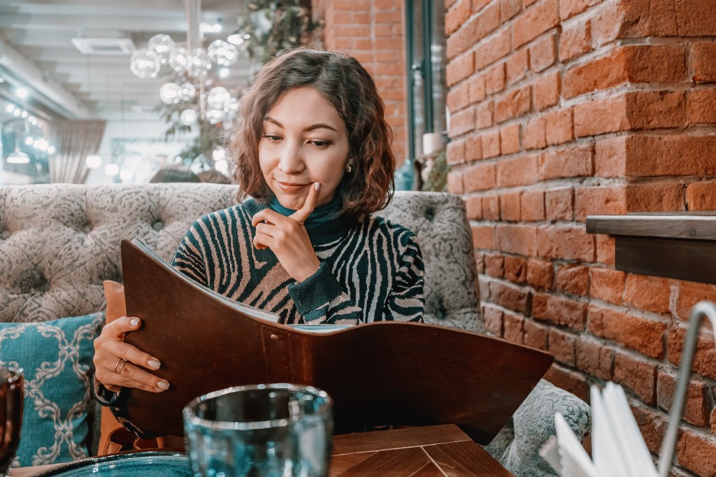 Happy woman looking at a big menu in a restaurant