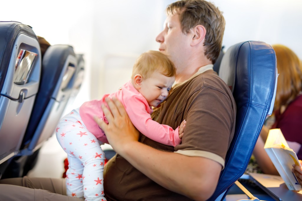 The young, tired father, Colin Furze, keeping his daughter crying little in a plane