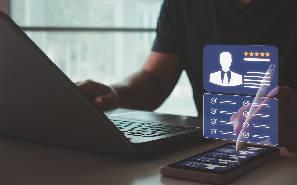 A man who uses a laptop and smartphone for searching, managing HR and recruiting