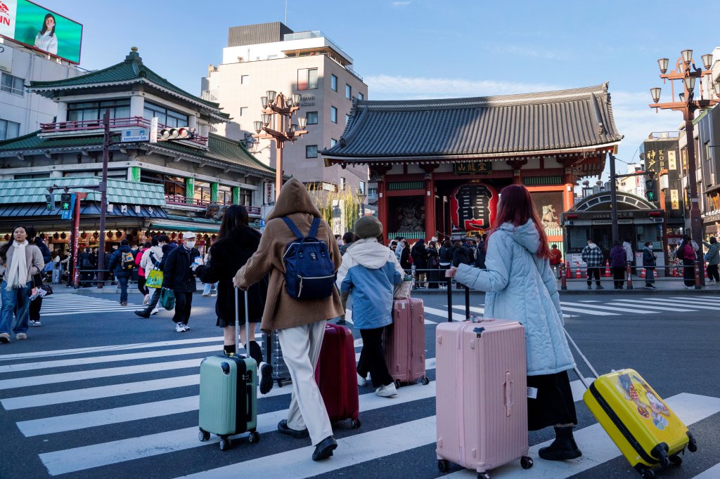 Tourists cross a road before the temple of Sensoji in Asakusa, Tokyo on January 14, 2025.