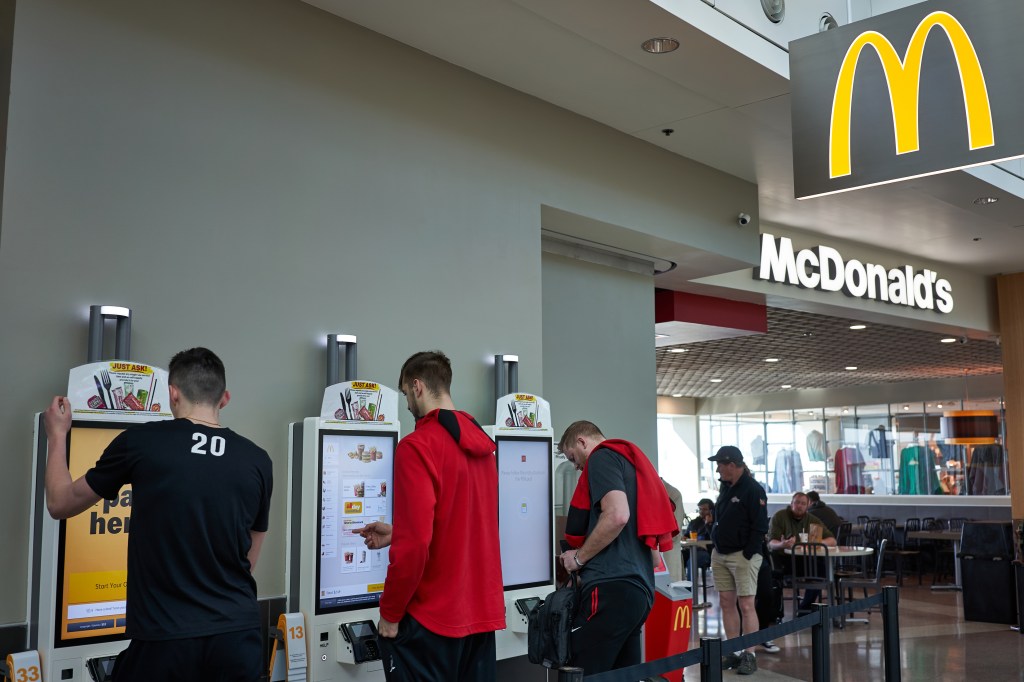 People use self-service kiosks to place their orders at a McDonald's restaurant at Portland International Airport