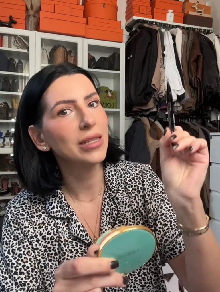 A woman holding a brush and a mirror in a tiktok video by Natythebratty