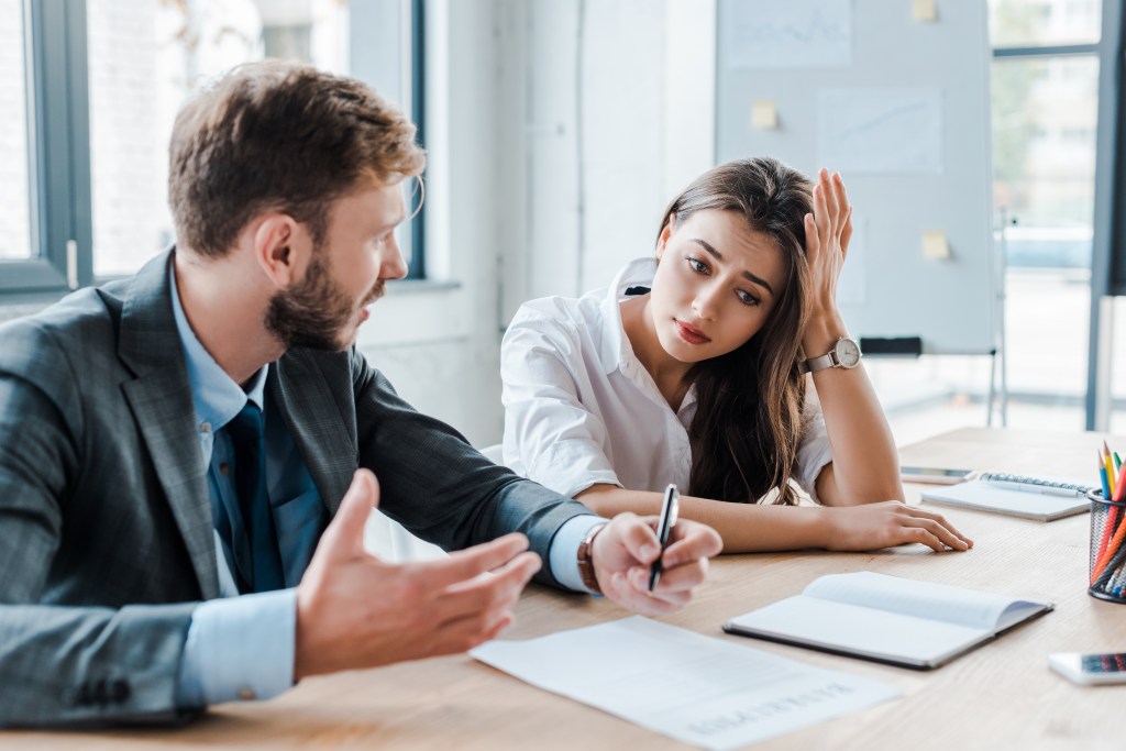 The selective focus of a sad woman sitting with a bored businessman on duty